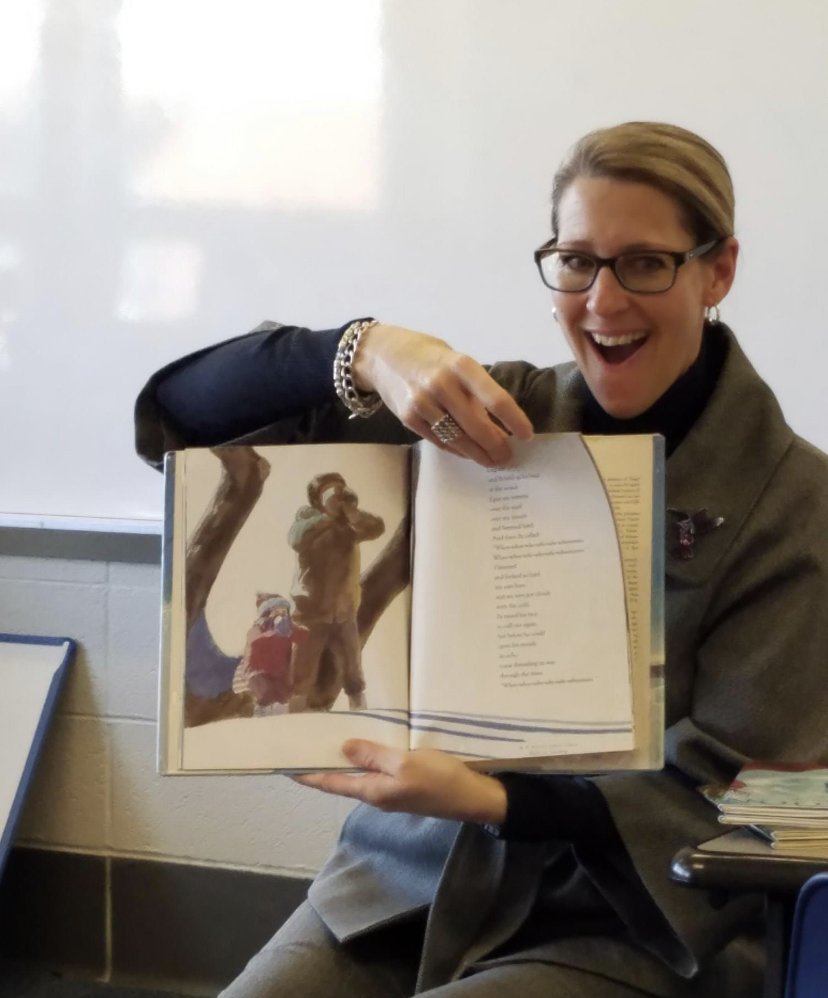 Dr. Felty reads a book in front of a class